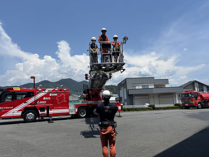 写真：ベルトとバスケットをロープでつなぎ安全を確保し梯子車搭乗の様子