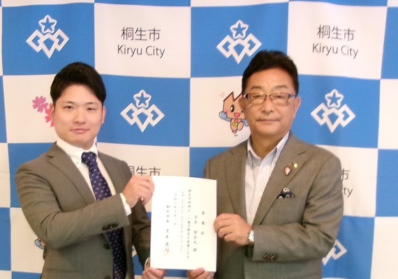写真:宮本隊員と市長が二人で一枚の委嘱状を掲げている様子