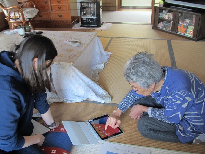 利用者(右)にタブレット端末の操作方法を説明する小島隊員の写真