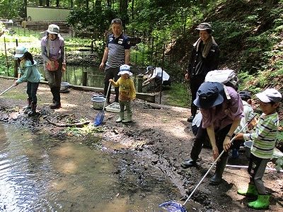 写真:沼の泥や落ち葉を編みですくいとる親子
