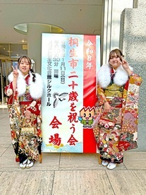 写真：二十歳を祝う会の看板の前で撮影　女性2人
